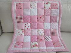 a pink and white patchwork quilt on a couch