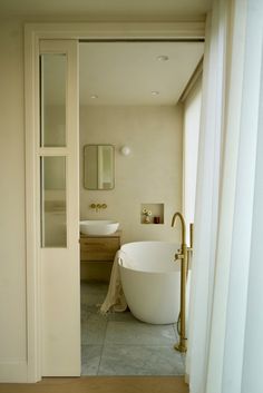 an open door leading to a bathroom with a bathtub and sink in the corner