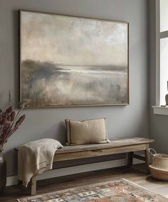 a large painting hanging on the wall above a wooden bench in a living room area