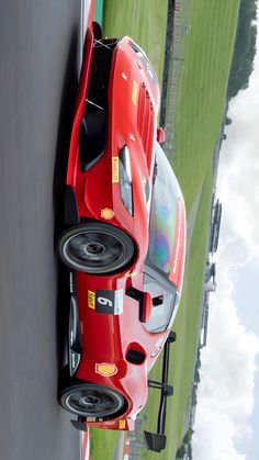 a red sports car is parked on the side of the road in front of a green field