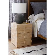 a bedroom with a bed, nightstand and lamp on the side table in front of it