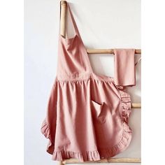 a pink dress hanging on a wall next to a wooden hanger with two pieces of clothing