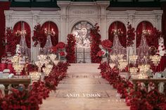 a red and white wedding set up with flowers, candles and decorations on the aisle