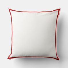 a white pillow with red piping on it