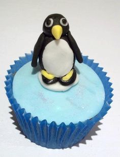 a penguin sitting on top of a blue cupcake