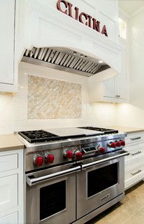 a kitchen with white cabinets and stainless steel stove top, oven hood and rangetop