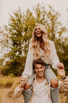 a man riding on the back of a woman's shoulders while she smiles at her