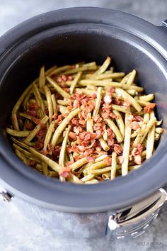 green beans and bacon in a slow cooker with the lid open, ready to be cooked