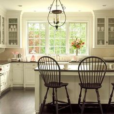 a kitchen with white cabinets and two chairs