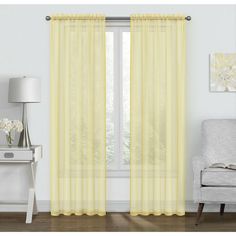 a living room with yellow curtains and a chair in front of a window that has white flowers on it