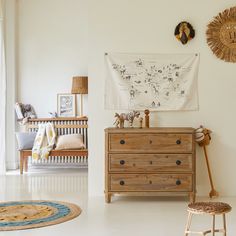 a baby's room with a crib, dresser and wall hanging on the wall