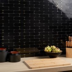 The drama of hand-selected black jade is featured in this collection’s mix of beautifully compatible materials—marble and lava stone. The Norway Black Jade 2x6 Polished Marble and Lavastone Mosaic Tile is distinctive for its precisely cut, rounded 2-by-6-inch bricks. The thinnest of grout lines add to this tile’s uniformly delicate look. Gem-like and captivating, our Norway collection features natural stone cut with waterjet technology to form a mosaic destined to take the spotlight in any appli Tile In Bar Area, Gold Grout Bathroom, Black Bar Backsplash, Oval Tile Backsplash, Black Backsplash Bar, Black Moody Bathroom, Kitchen Backsplash With Black Cabinets, Black Matte Backsplash, White Tile Black Grout