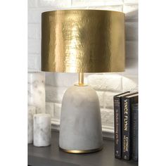 a white and gold lamp sitting on top of a table next to a book shelf