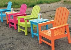 four brightly colored plastic chairs sitting in the dirt