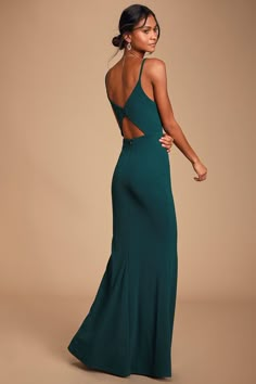 a woman in a long green dress is standing with her back turned to the camera