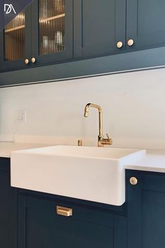 a kitchen with blue cabinets and a white sink in the center is gold faucet