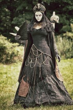 a woman dressed in black and white is holding a bird on her arm while standing in the grass