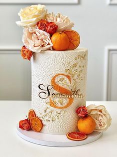 a white cake with oranges and flowers on top