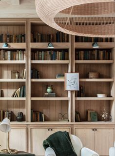 a living room filled with lots of wooden bookshelves and white chairs next to each other