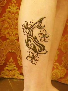 a woman's leg with a tattoo on it that has flowers in the shape of a letter