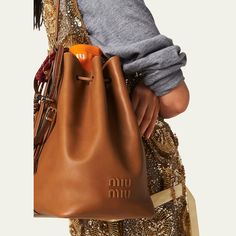 Miu Miu bucket bag in fine calf leather  Adjustable buckle shoulder strap  Drawstring closure  Approx. 11.4"H x 6.7"W x 5.1"D Made in Italy Tela, Leather Sling Bags Women, Sling Bags Women, Leather Sling Bags, Cocktail Jacket, Drawstring Bucket Bag, Leather Bucket Bag, Leather Bucket, City Style