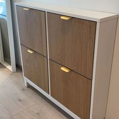 a white and brown cabinet sitting on top of a hard wood floor