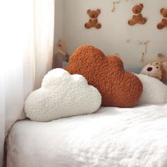 two teddy bears sitting on top of a bed with white sheets and fluffy clouds in front of them