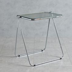 a metal and wood table with a glass top on it's legs in front of a gray wall