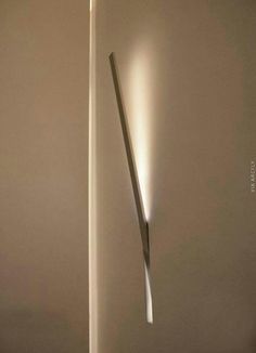 a light that is on the side of a wall next to a floor lamp with a long stick sticking out of it