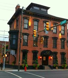 an old brick building on the corner of a street with traffic lights in front of it