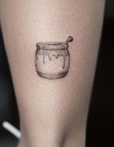 a woman's leg with a jar tattoo on the side of her thigh that has a spoon in it