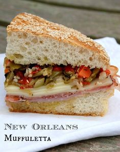 a sandwich with meat, cheese and vegetables on a white paper towel sitting on a wooden table