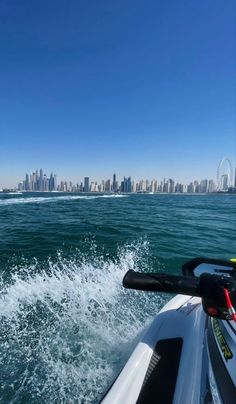 a boat traveling through the water with a city in the background