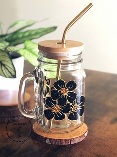 a glass mug with a straw in it sitting on a table next to a potted plant