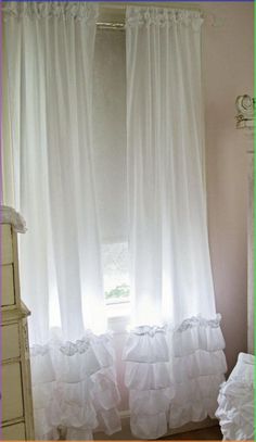 a white curtain with ruffles hanging in front of a window