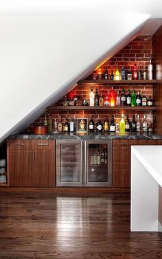 an attic bar with built - in wine coolers and liquor bottles on the shelves