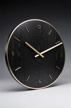 a black and gold clock with numbers on it's face is shown against a gray background