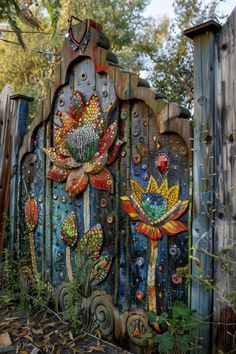 an artisticly painted wooden gate with flowers and birds on the top, in front of a fence