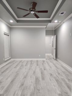 an empty room with wood floors and ceiling fan