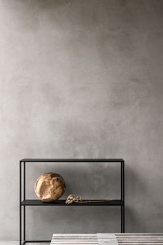 a table with a vase on it next to a book shelf and a wooden object