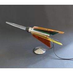 a multicolored pen is hooked up to a metal object on a gray surface