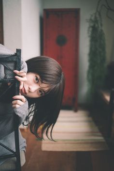 a young woman leaning against a chair in a room with a rug on the floor