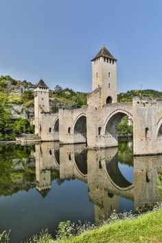 an old bridge over a river with a tower on the top and reflection in the water