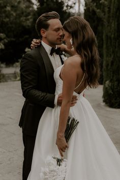 a man in a tuxedo and a woman in a wedding dress are embracing each other