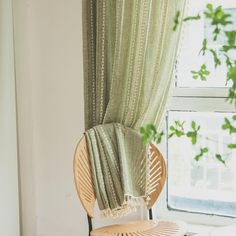 a chair sitting in front of a window next to a plant