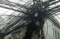 wires are tangled up in the air on top of a pole