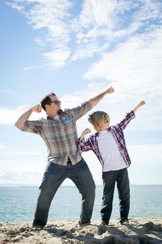 two people standing on the beach with their arms in the air and one person holding his head