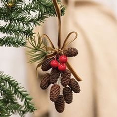 a pine cone ornament hanging from a christmas tree with red berries on it