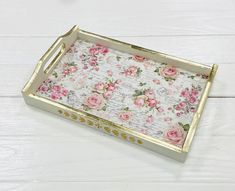 a tray with pink flowers on it sitting on top of a white wooden floor next to a wall