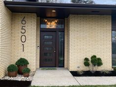 the front entrance to a home with two potted plants